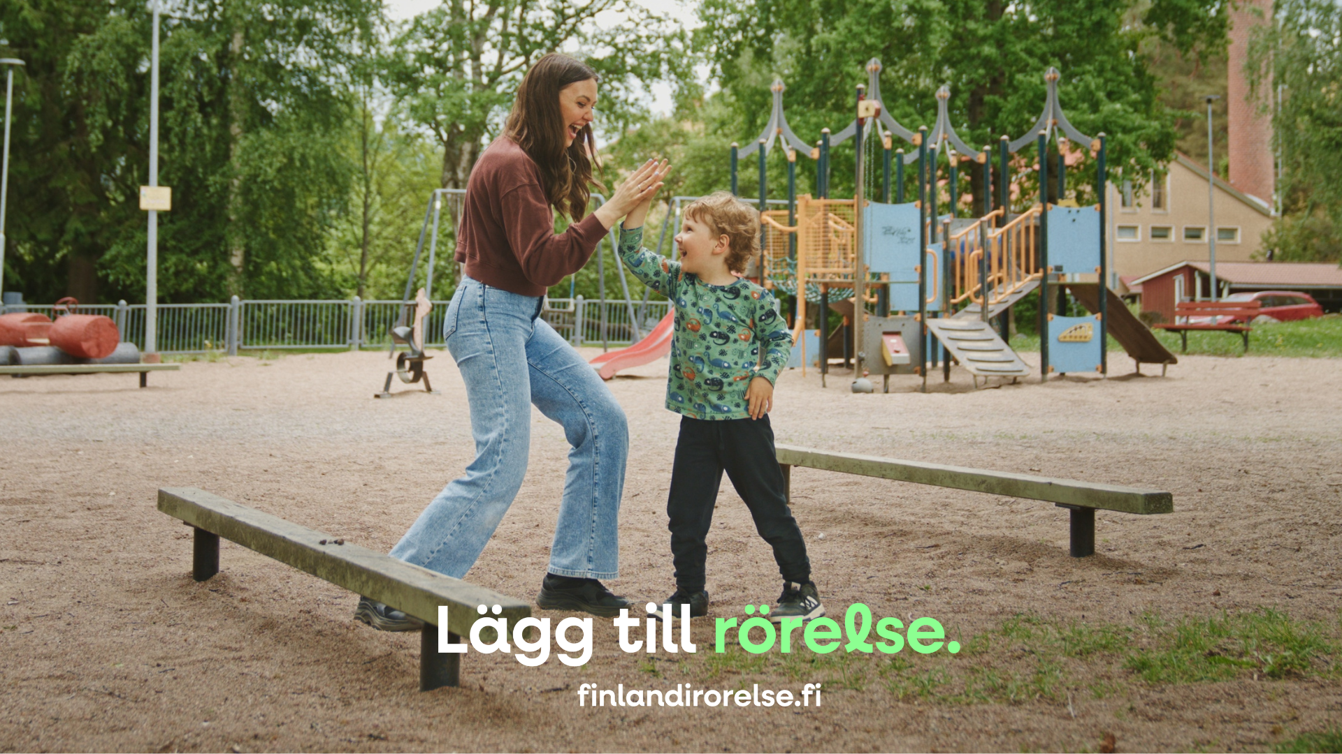 En vuxen och ett barn leker på lekplatsen.