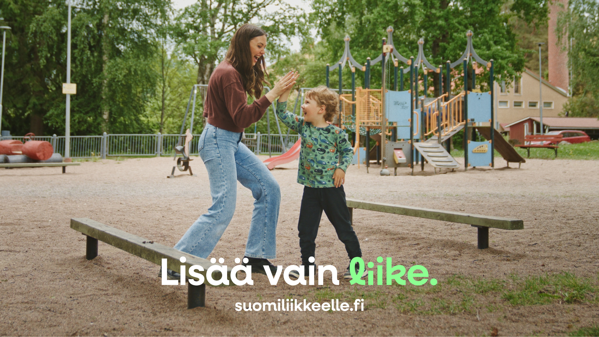 Huoltaja ja lapsi leikkivät leikkipuistossa.